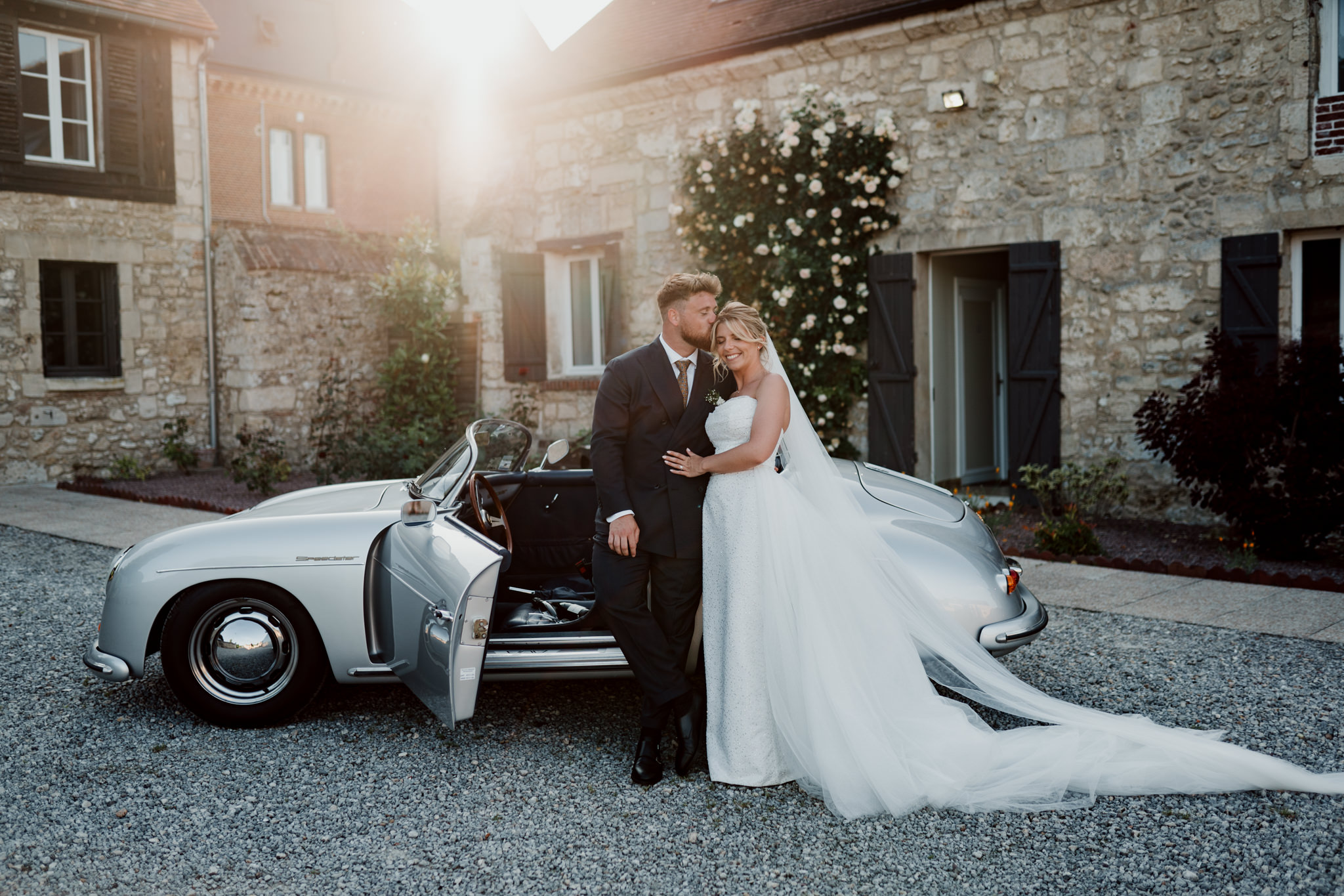 Séance couple au coucher du soleil devant une voiture vintage lors d'un mariage
