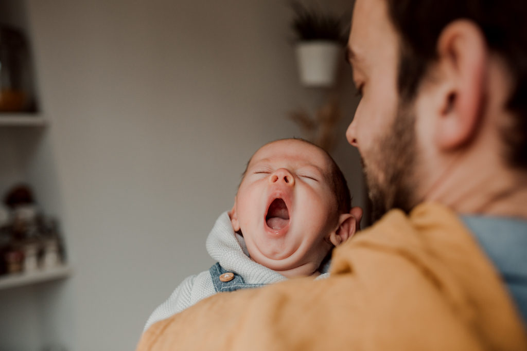 Bébé qui baille lors d'une séance photo en famille à domicile.