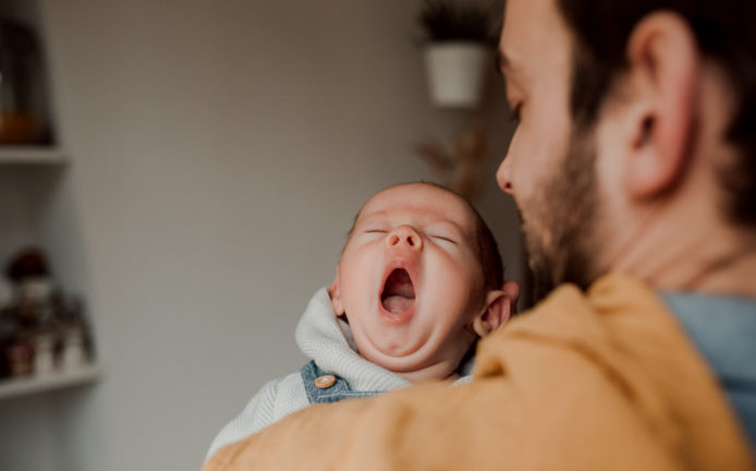 Bébé qui baille lors d'une séance photo en famille à domicile.