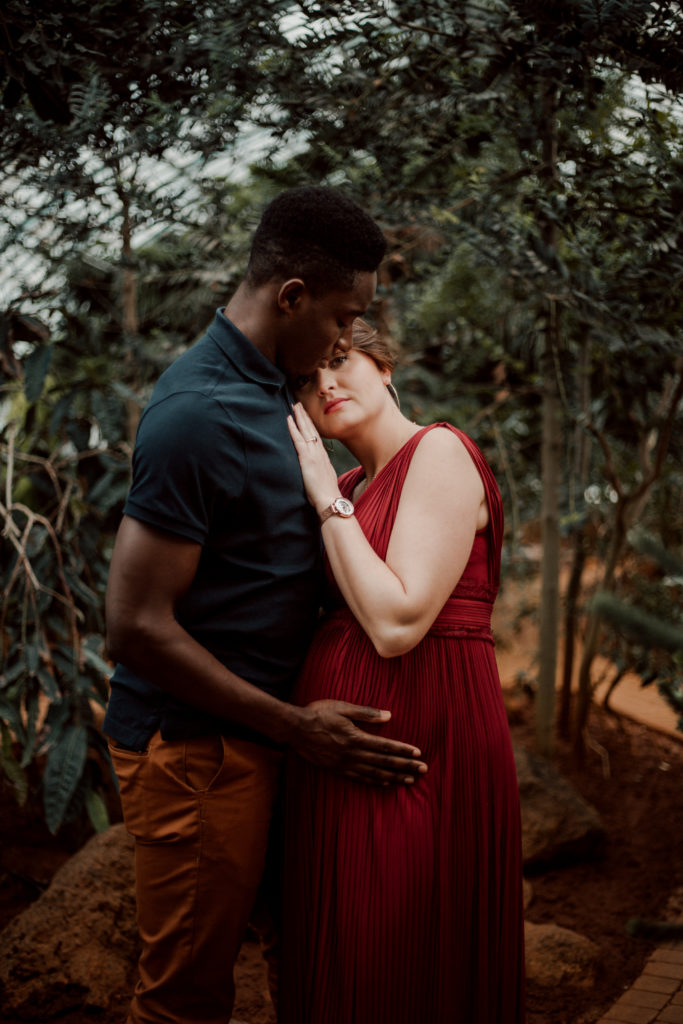 Couple se faisant un calin aux Serres D'Auteuil à Paris lors d'une séance photo grossesse.