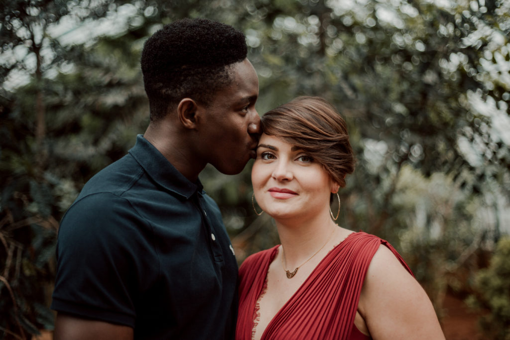 Couple se faisant un bisou aux Serres D'Auteuil à Paris lors d'une séance photo grossesse.