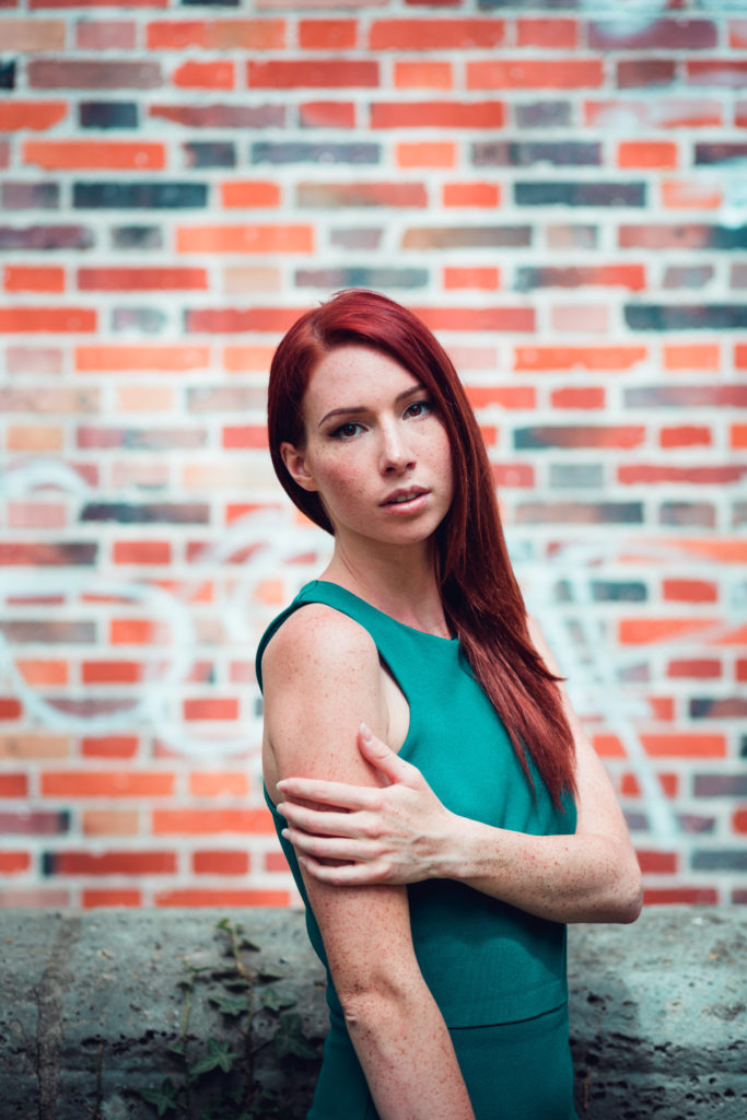 Portrait d'une femme devant un mur de brique à la Coulée Verte à Paris