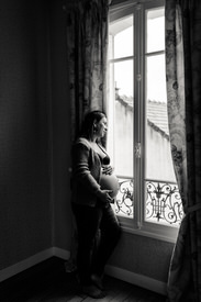 Femme enceinte devant la fenetre durant une séance photo grossesse